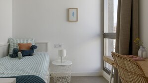 Un dormitorio con cama, mesita de noche, lámpara y un cuadro enmarcado en la pared.