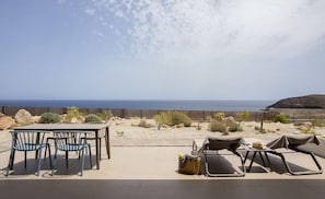 An outdoor seating area with a table and chairs, a wicker basket, and a hat on a small table. - Nivaria Beach Apartments and Villas (Arico)