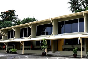A building with a flat roof, large windows, and potted plants. - Huon Gulf Hotel and Apartments (Lae)