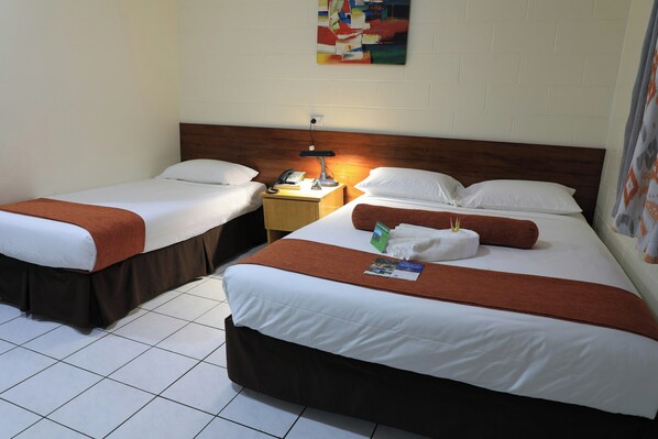 A hotel room with two single beds, a nightstand with a lamp, and a wall-mounted artwork. - Huon Gulf Hotel and Apartments (Lae)