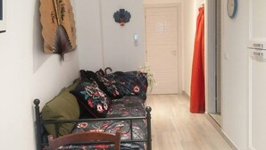 Une pièce comprenant un lit, une chaise en bois, une horloge murale et une porte avec un rideau rouge.