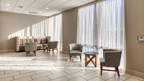 A hotel room with a sofa, two armchairs, a small table, and large windows with sheer curtains. - Holiday Inn Express and Suite Manitou Spring (Manitou Springs)