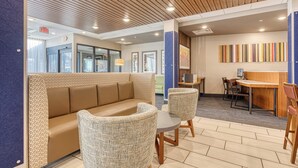 A modern lobby with a wooden ceiling, a seating area with a sofa and chairs, a reception desk, and a colorful wall art piece. - Holiday Inn Express and Suite Manitou Spring (Manitou Springs)