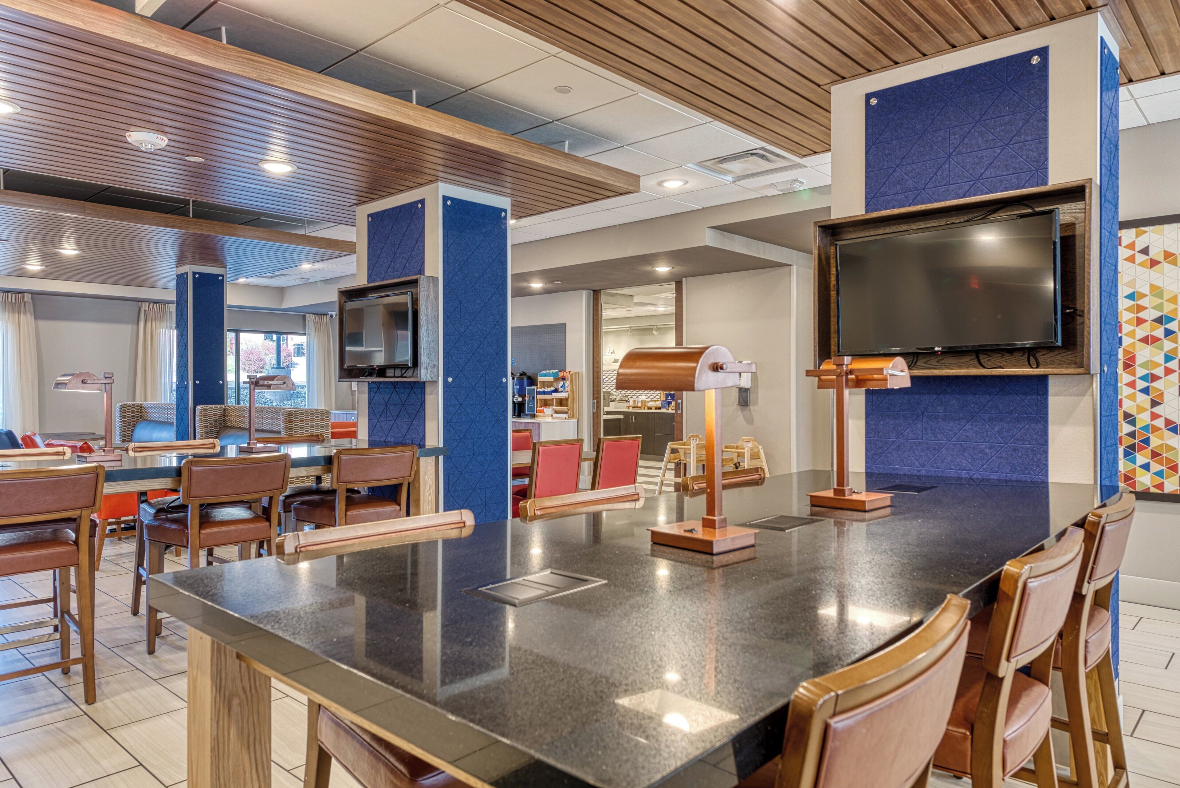 Un ristorante moderno con un'isola centrale, sedie di legno e un televisore a schermo piatto montato al muro.