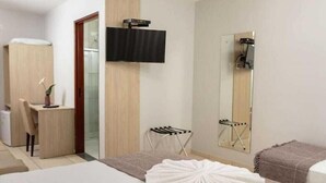 A hotel room with a bed, a desk, a chair, a TV, a mirror, and a shower. - Hotel Ciribai Maceio (Maceió)