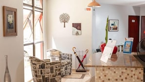 A reception area with a cash register, a chair with a unique design, a wall-mounted tree decoration, and a large window. - Hotel Ciribai Maceio (Maceió)