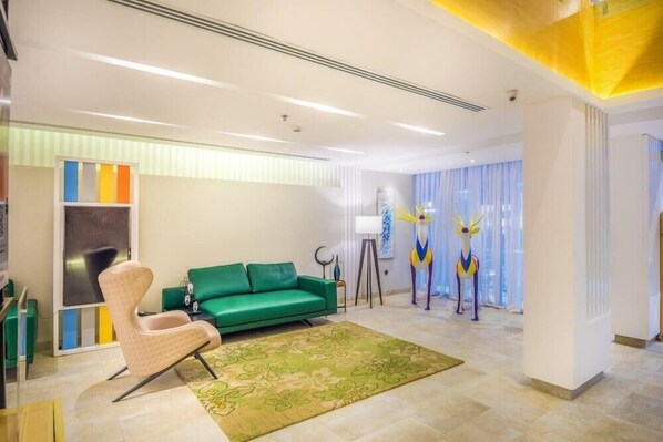 Uma sala de estar moderna com um sofá verde, uma poltrona bege e um tapete decorativo.