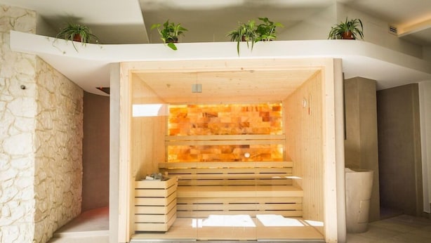 Un sauna con bancos de madera y pared de piedra.