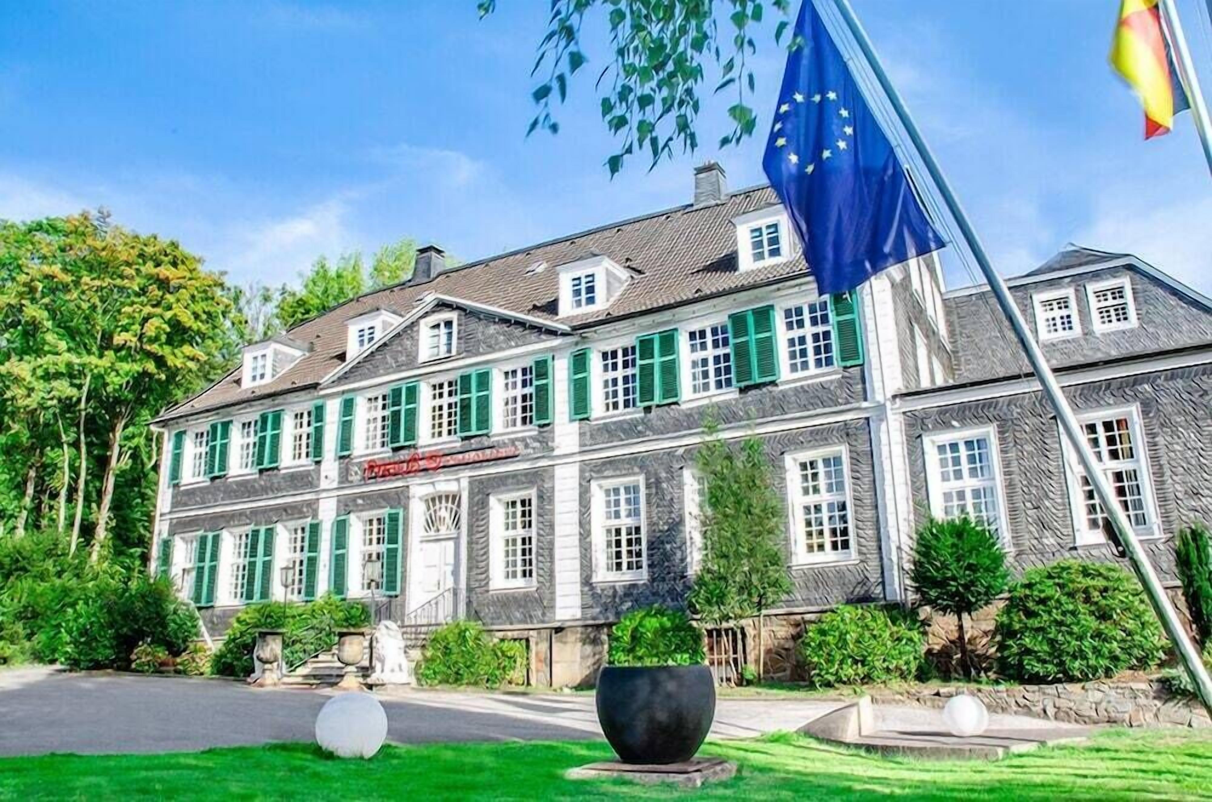 Ein großes, historisches Gebäude mit zahlreichen Fenstern und grünen Fensterläden, vermutlich ein Hotel oder ein öffentliches Gebäude.
