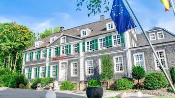 Ein großes, historisches Gebäude mit zahlreichen Fenstern und grünen Fensterläden, vermutlich ein Hotel oder ein öffentliches Gebäude.
