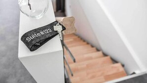 Un trousseau de clés avec une étiquette indiquant « Suite n° 122 », posé sur une surface blanche à côté d’un escalier.