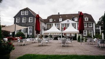 Ein Innenhof mit Außenbestuhlung und einem großen Gebäude im Hintergrund.