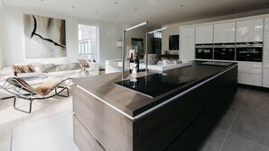 Une cuisine moderne dotée d’un grand îlot central, de meubles blancs et d’un design minimaliste.