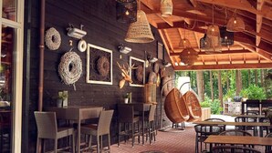 Un comedor interior con mobiliario de mimbre, lámparas colgantes y decoración en las paredes, incluyendo cuernos de animales y cestas tejidas.