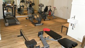Un gimnasio con varios equipos de ejercicio, incluyendo cintas de correr, bicicletas estáticas y máquinas de pesas.