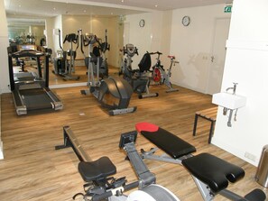 A gym with various exercise equipment, including treadmills, stationary bikes, and weight machines.