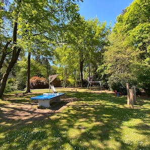 Un parc avec une table bleue, des balançoires et un toboggan.