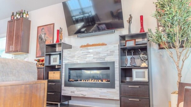 A modern living room with a fireplace, a flat-screen TV mounted above it, and a red rug on the floor. - The Jazzy Junction-Great Downtown Location! (Pensacola)