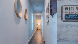 A hallway with a wooden floor, light blue walls, and a sign indicating a WiFi password. - The Jazzy Junction-Great Downtown Location! (Pensacola)