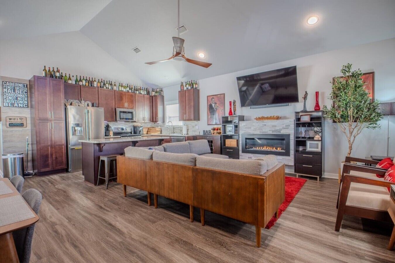 A modern kitchen with wooden cabinets, a built-in oven, and a dining area with a wooden table and chairs.