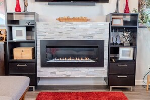 Ein modernes Wohnzimmer mit Kamin, dunklen Holzmöbeln und einem roten Teppich.