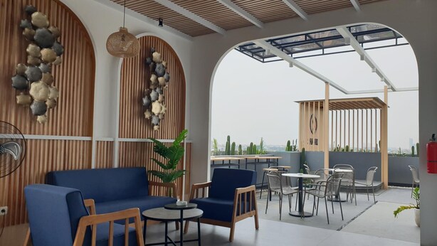 Una terraza en la azotea con mobiliario, un ventilador y vistas a la ciudad.