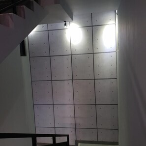 A room with a tiled wall, a staircase, and a light fixture. - Sambina Prime Hotel by Danapati (Jakarta)