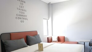 A modern hotel room with a bed, a small table, a chair, and a wall with motivational text. - Sambina Prime Hotel by Danapati (Jakarta)