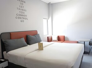 A modern hotel room with a bed, a small table, a chair, and a wall with motivational text. - Sambina Prime Hotel by Danapati (Jakarta)