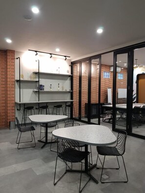A modern interior with round tables and chairs, a brick wall, and a glass partition. - Sambina Prime Hotel by Danapati (Jakarta)