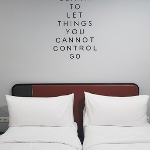 A bed with white bedding and a red headboard, and a motivational quote on the wall above. - Sambina Prime Hotel by Danapati (Jakarta)