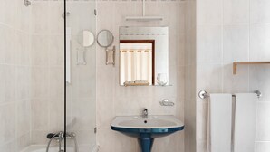 Un baño con bañera, lavamanos, espejo y toallero.