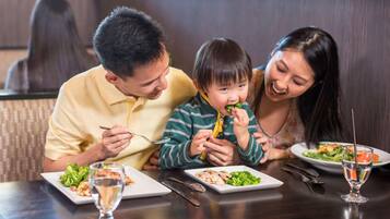 A family dining at a table with plates of food, cutlery, and a glass of water.