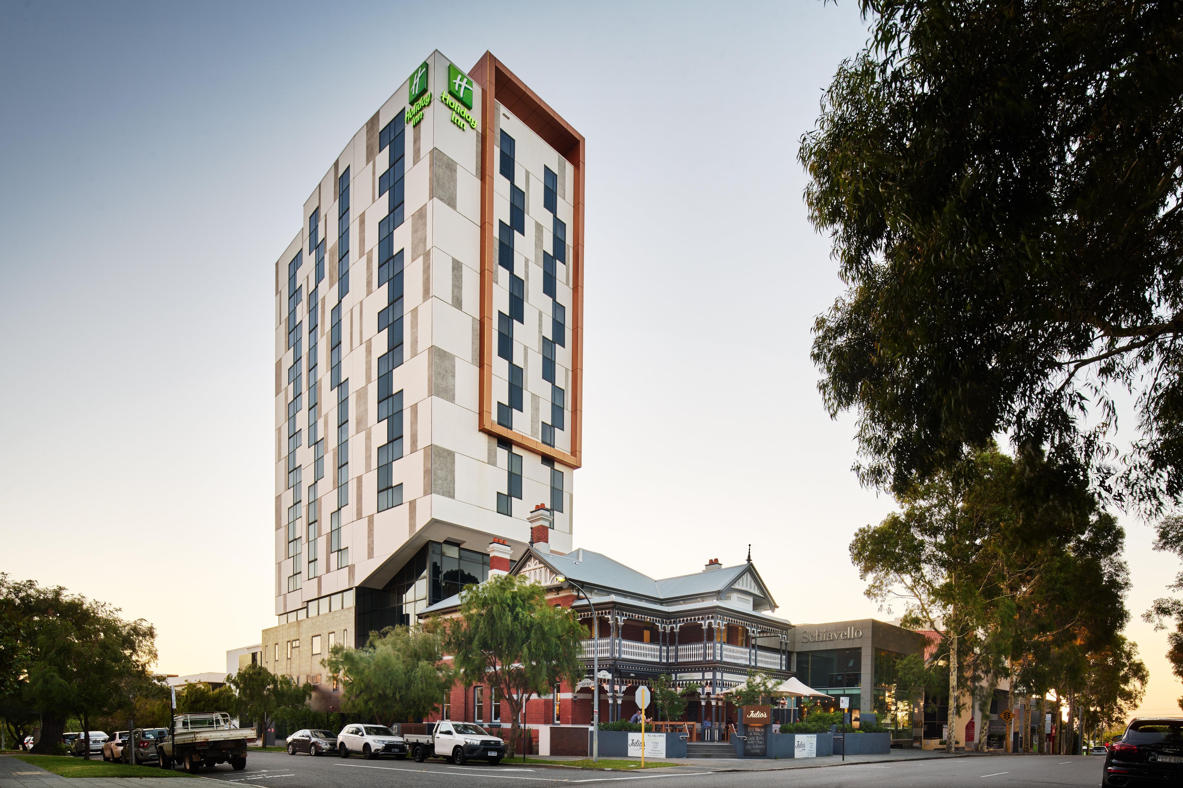 A hotel with a modern high-rise and a traditional building with a balcony.
