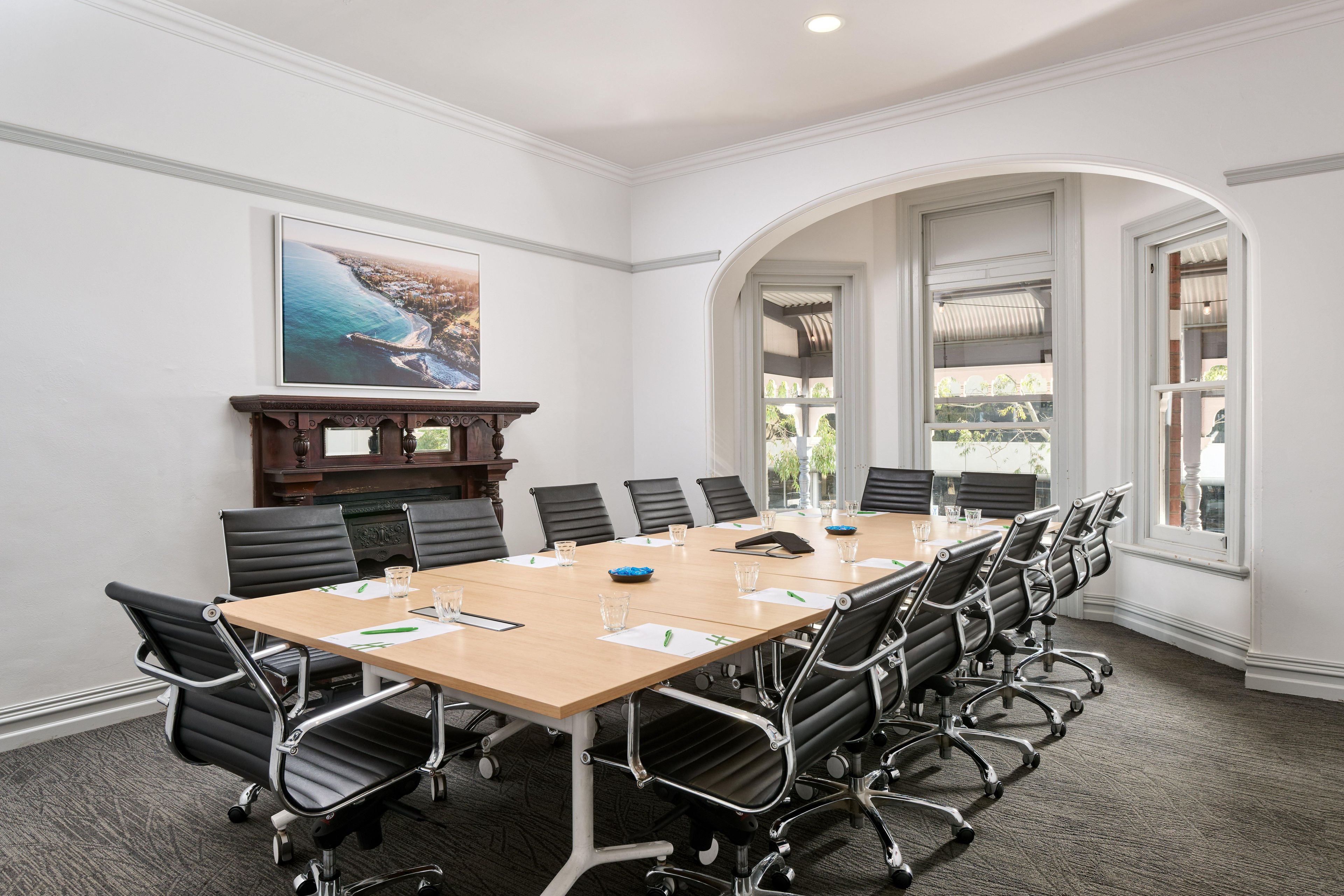 A conference room with a long table, black chairs, and a painting on the wall.