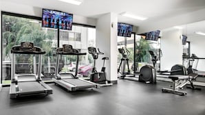 A gym with treadmills, an elliptical, and a stationary bike, with large windows and TVs on the walls. - Holiday Inn West Perth (Perth)