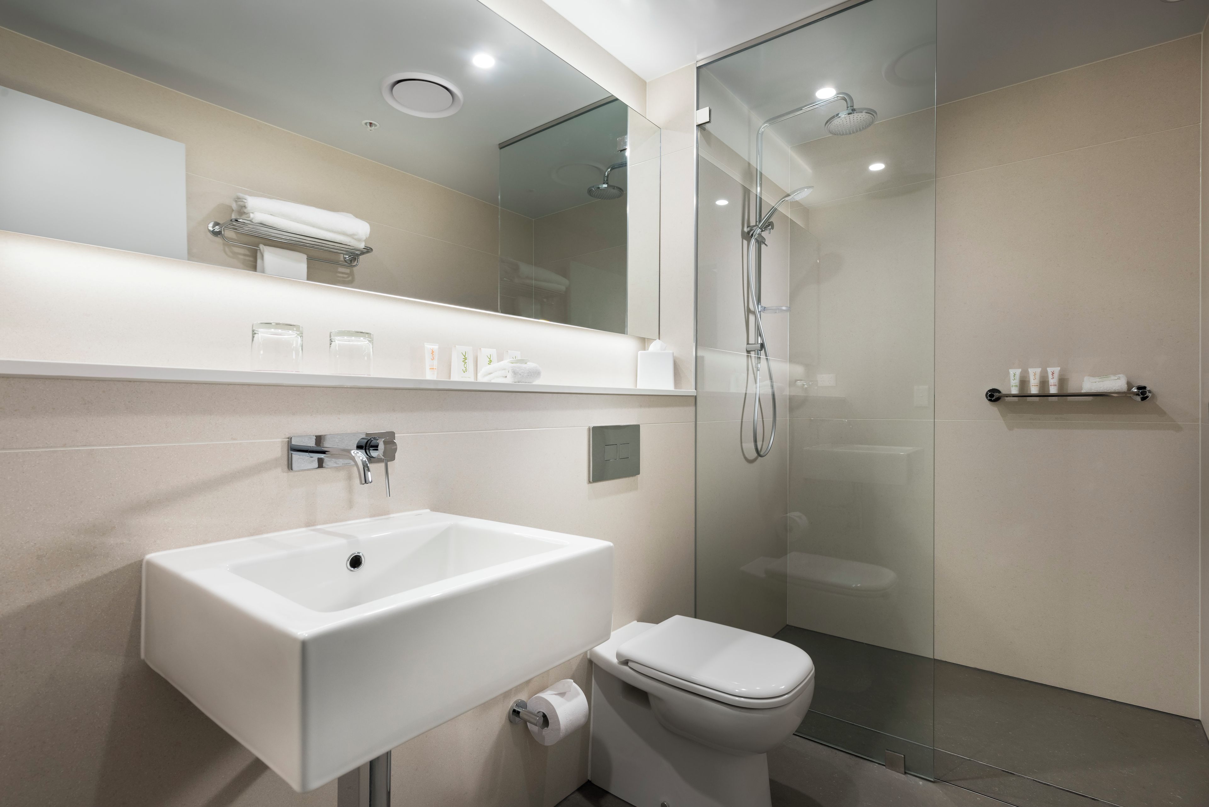 Une salle de bain moderne avec une douche à parois de verre, un lavabo blanc et des toilettes.