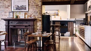 A restaurant with a brick wall, wooden furniture, a fireplace, and hanging pendant lights. - Holiday Inn West Perth (Perth)