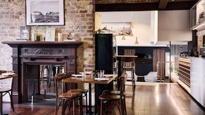 Un restaurante con pared de ladrillo, mobiliario de madera, chimenea y lámparas colgantes.