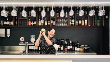 A bar area with shelves of liquor bottles, a bartender preparing a drink, and hanging glassware.