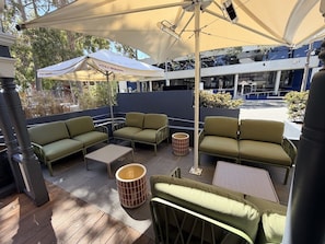An outdoor seating area with green sofas, round tables, and umbrellas. - Holiday Inn West Perth (Perth)