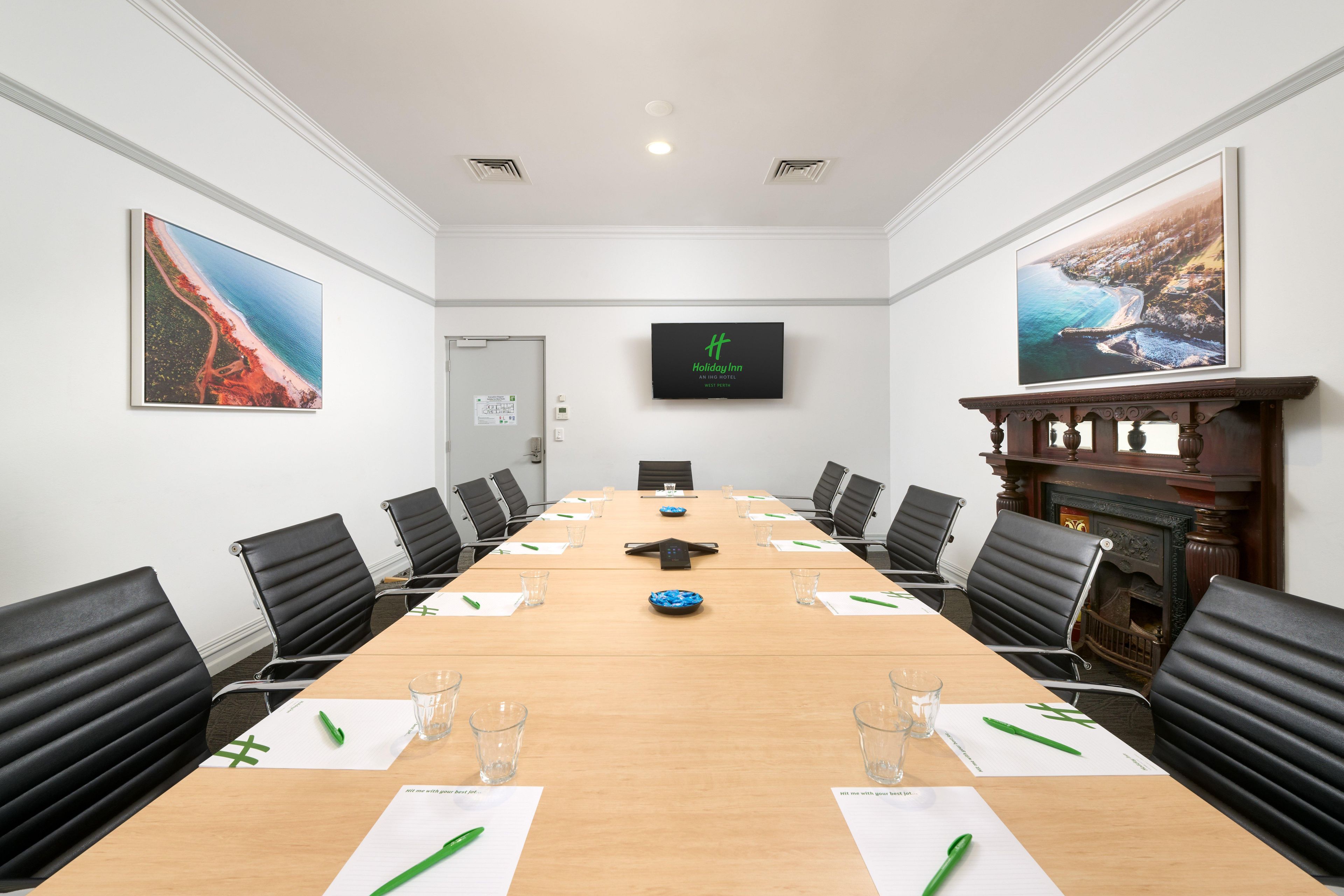 A conference room with a long table, black chairs, and framed pictures on the walls.