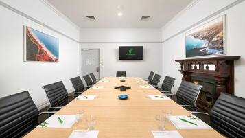 A conference room with a long table, black chairs, and framed pictures on the walls.