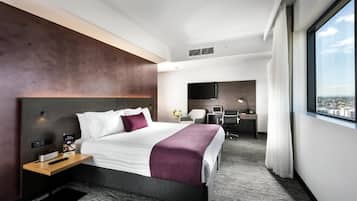 Una habitación de hotel moderna con una cama grande, un escritorio, una silla y vistas a la ciudad.