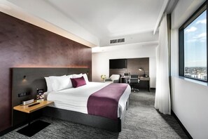 Une chambre d’hôtel moderne avec un grand lit, un bureau, une chaise et une vue sur la ville.