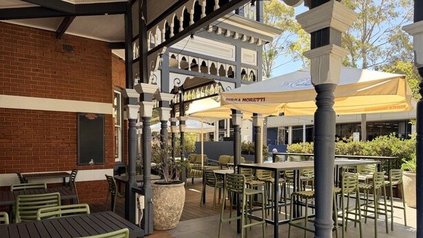 An outdoor patio area with tables and chairs, a brick wall, and a covered seating area with a sign reading 'BIRRA MORETTI'. - Holiday Inn West Perth (Perth)