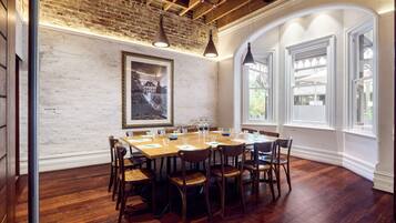 A dining area with a brick wall, wooden ceiling, and large windows.