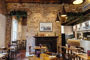 A restaurant interior with brick walls, wooden tables, and hanging plants. - Holiday Inn West Perth (Perth)