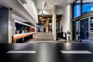 Un interior moderno con mostrador de recepción, escalera y ventanas amplias.