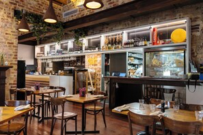 A restaurant interior with brick walls, wooden tables, hanging lights, and a bar area with shelves of bottles and glasses. - Holiday Inn West Perth (Perth)